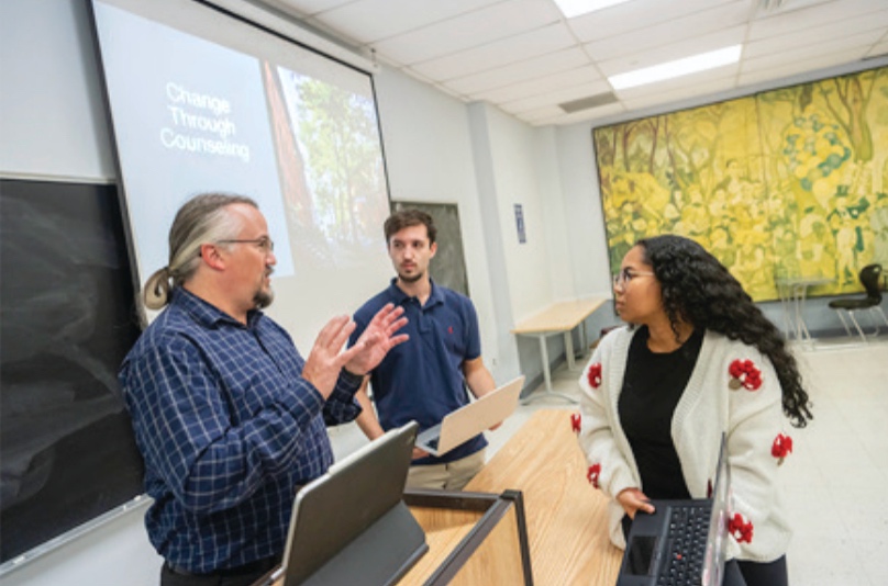 Psychology students chat with a professor.