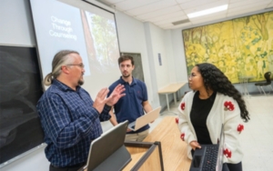 Psychology students chat with a professor.