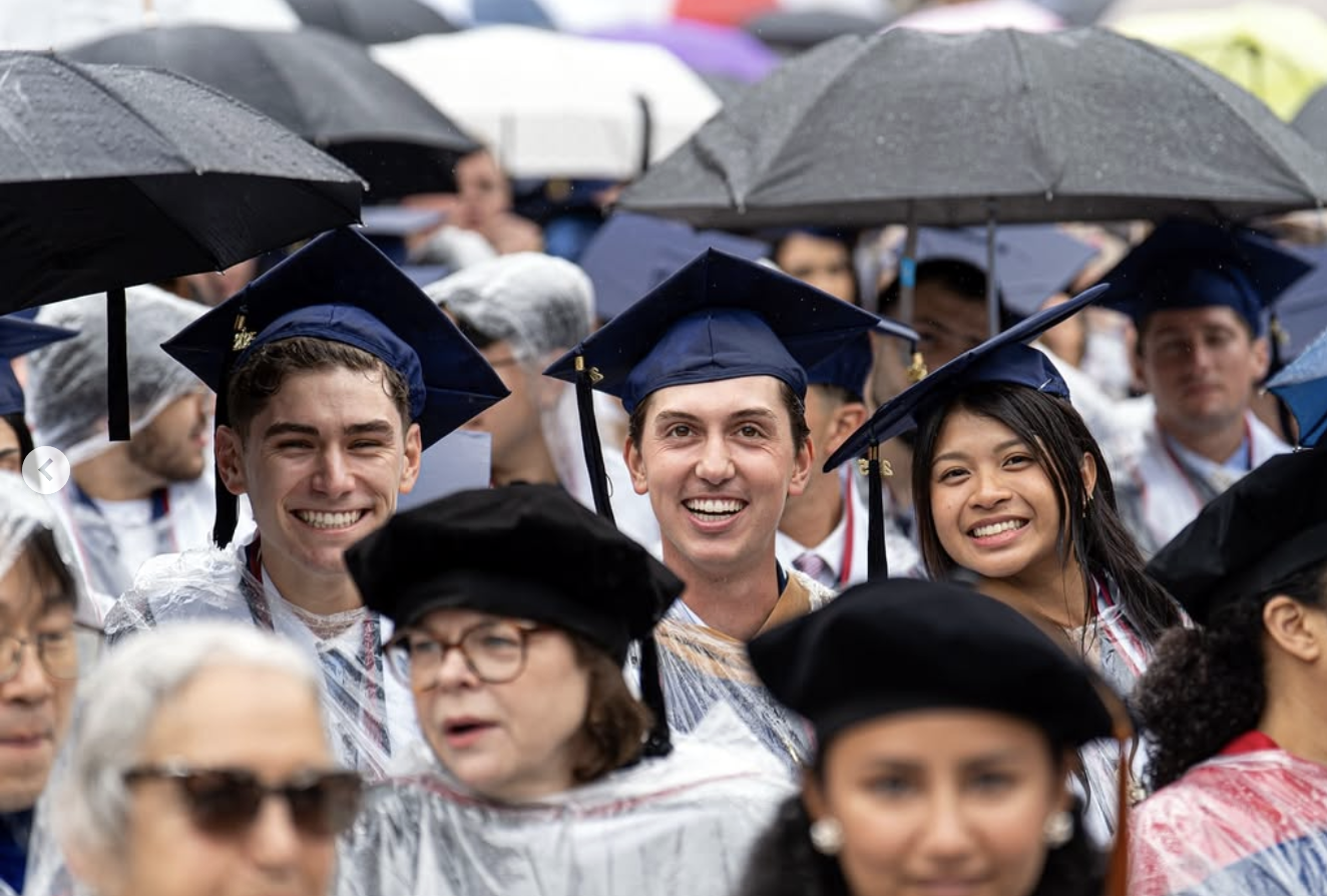 Students smile among a sea of graduation caps and gowns and ponchos.