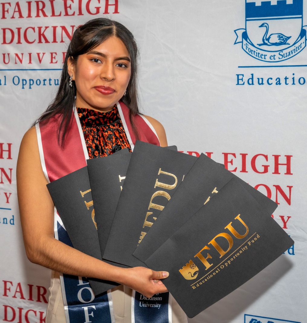 a student poses for the camera. she holds up several certificates that read 