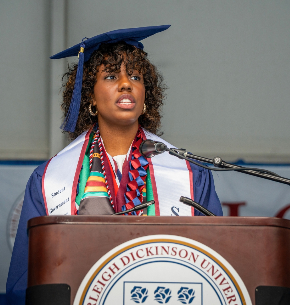 a graduate gives a speech at a podium.