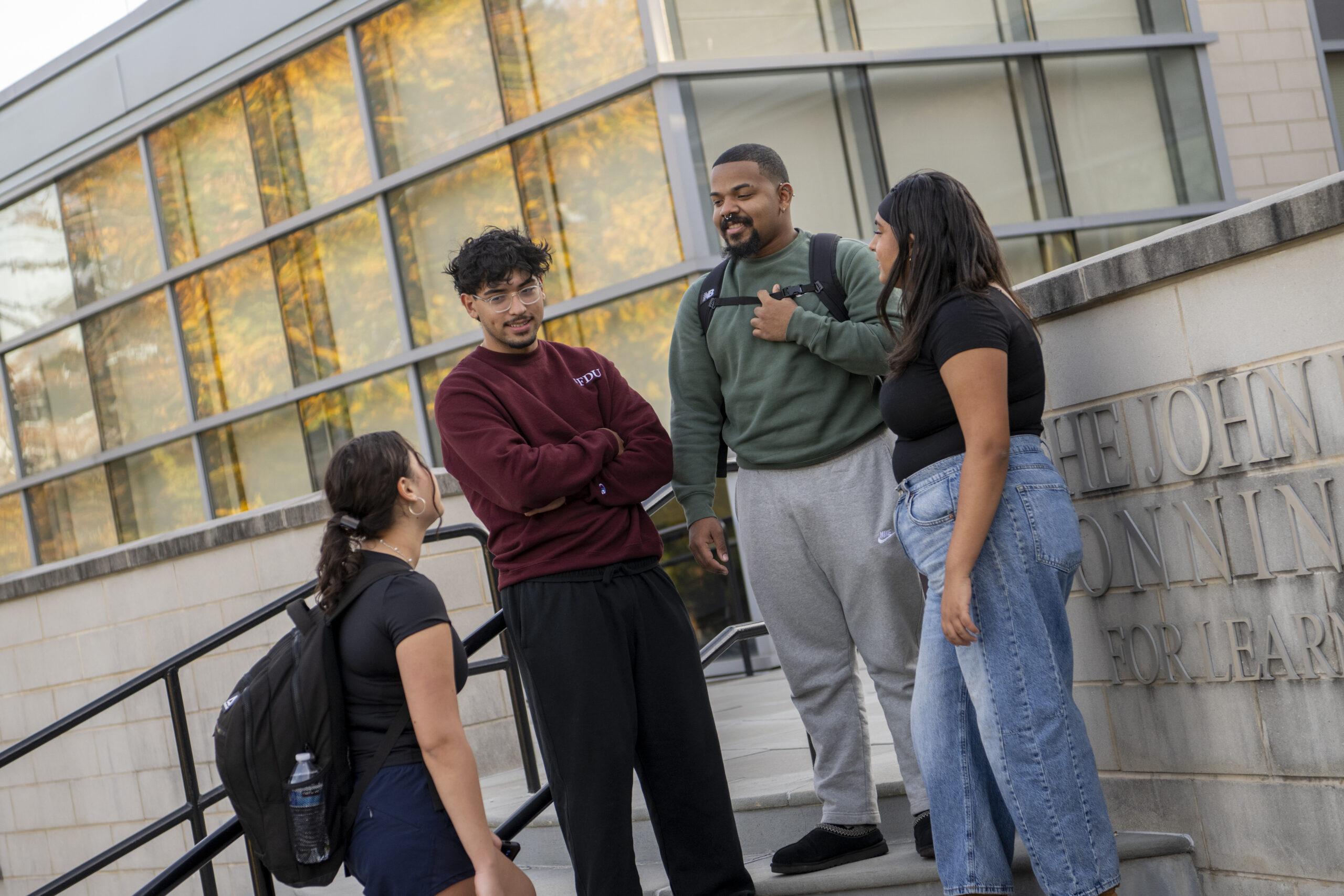 A group of four students mingling on an outside staircase.