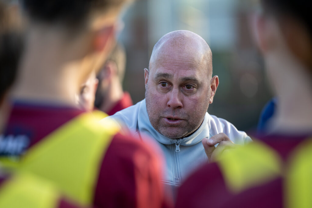 A man speaks to his team standing in a circle.