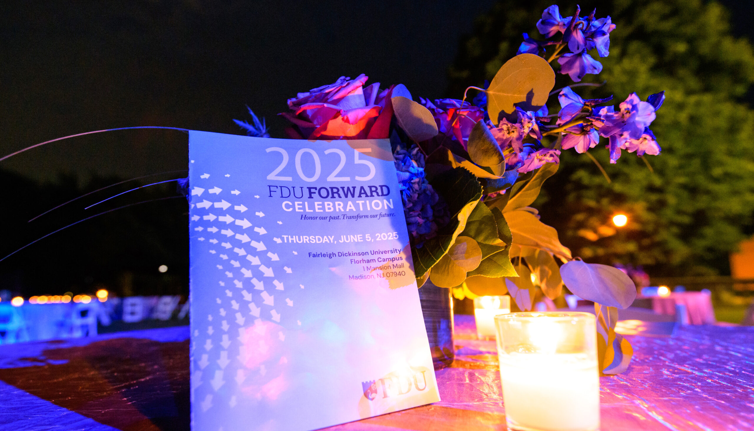A candle, a bouquet of flowers and an FDU Forward program on a table.
