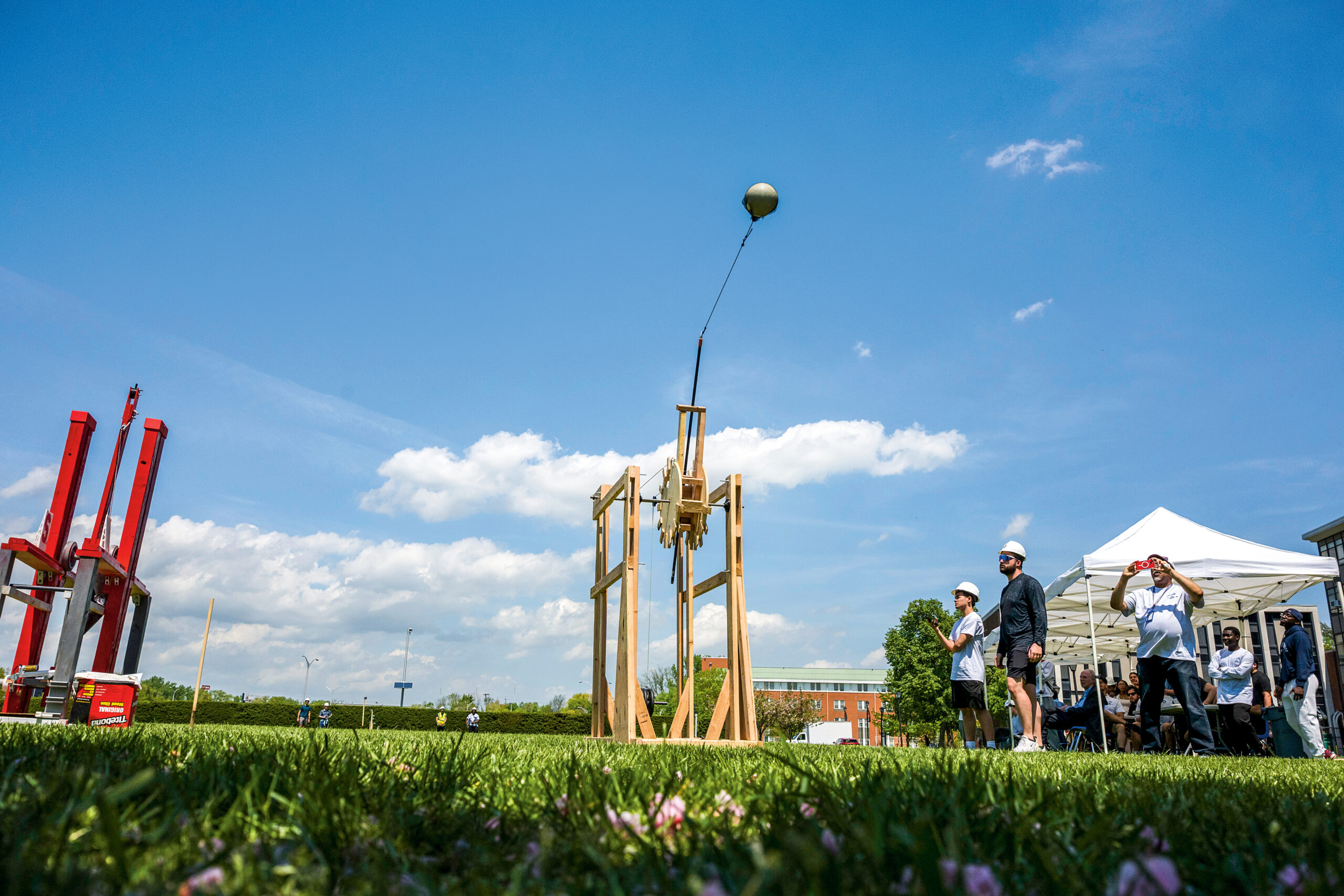 Students launch a volleyball from a trebuchet.