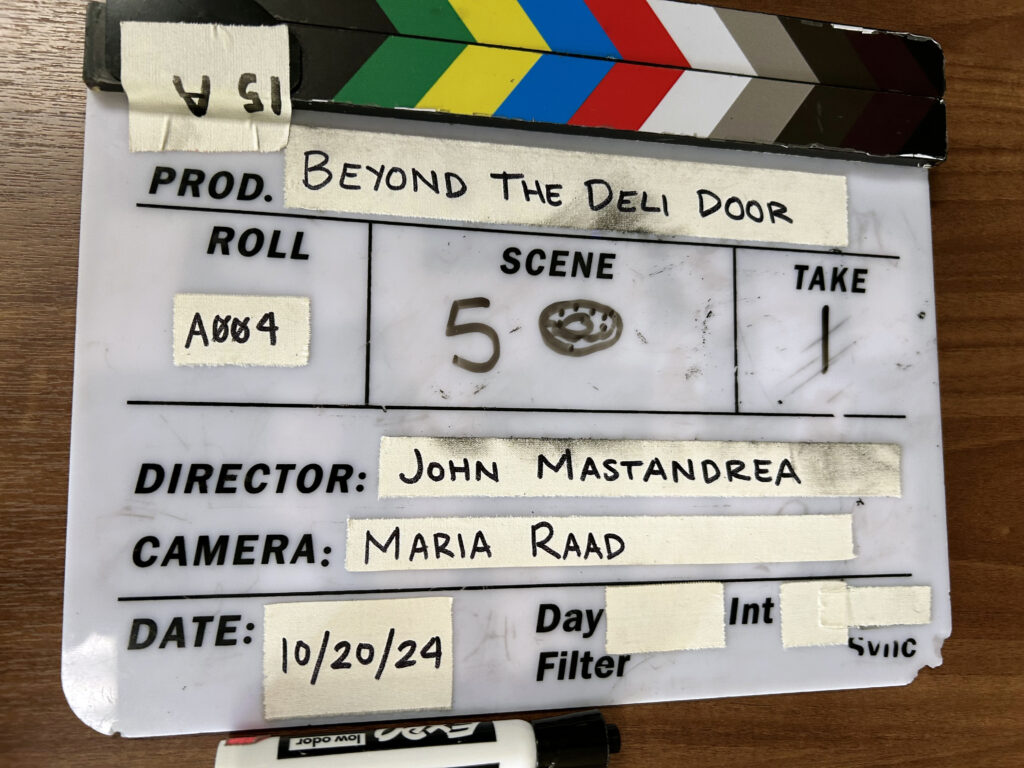 Film clapboard with writing on it for short film called "Beyond the Deli Door."