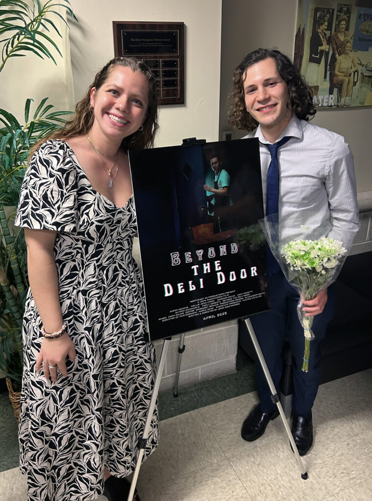 A woman and a man pose with a film poster.