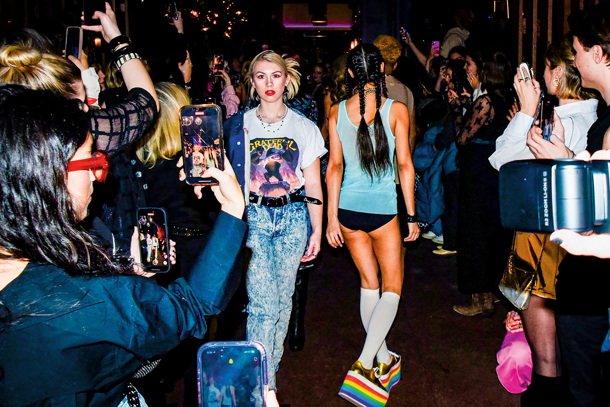 A young woman wearing vintage jeans and a t-shirt walks in Fashion Week.