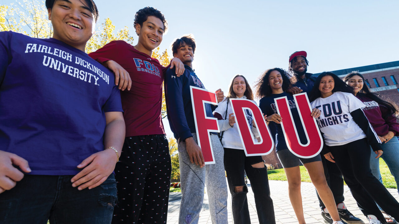 A group of students stand together and hold up FDU letters.