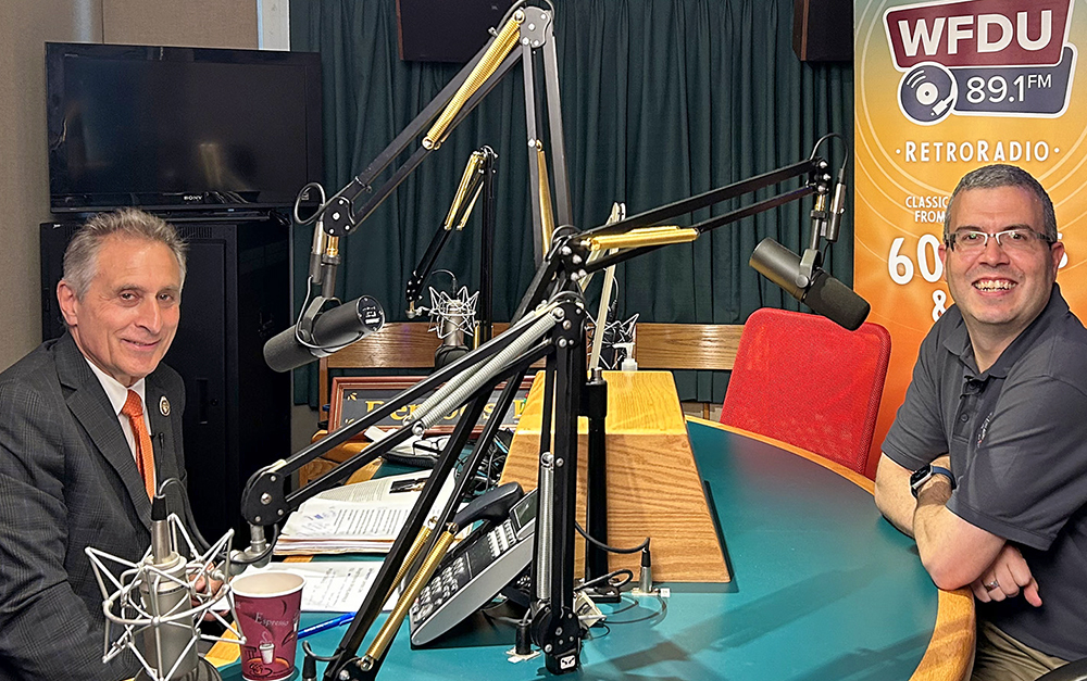 Two men sit inside a radio station.
