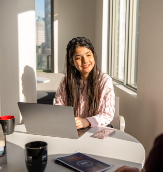 A student or professional smiling while interacting with a colleague in a bright, welcoming office. The scene emphasizes interpersonal communication and customer-focused interactions