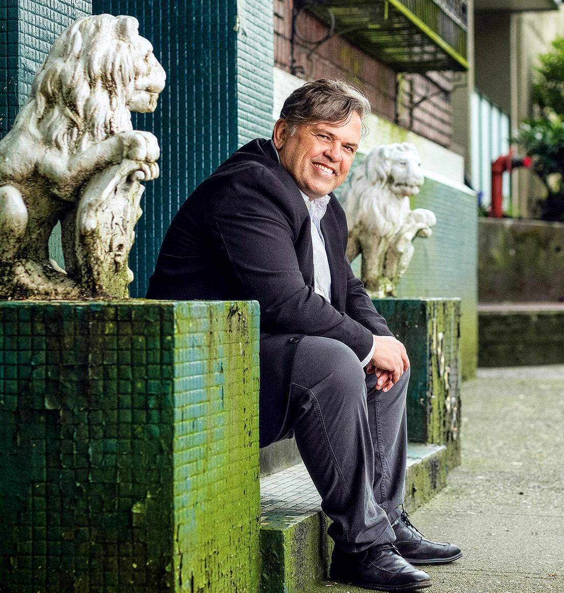 A man wears a suit and sits on a stoop in the city.