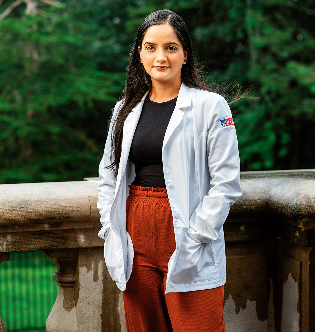 A young woman in a white coat stands out on a terrace.