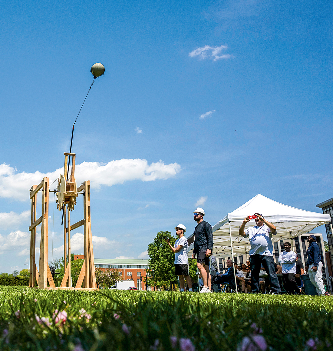 Students launch a volleyball from a trebuchet.