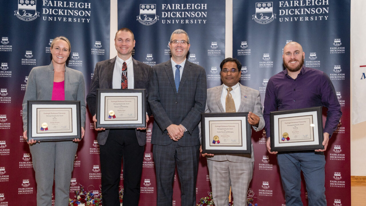 One woman and four men stand together to receive awards.