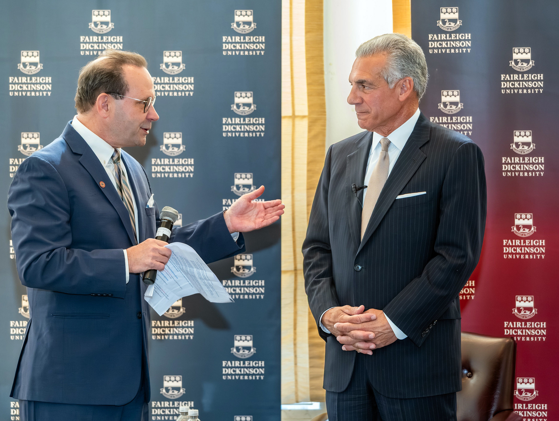 Two men in suits stand talking.