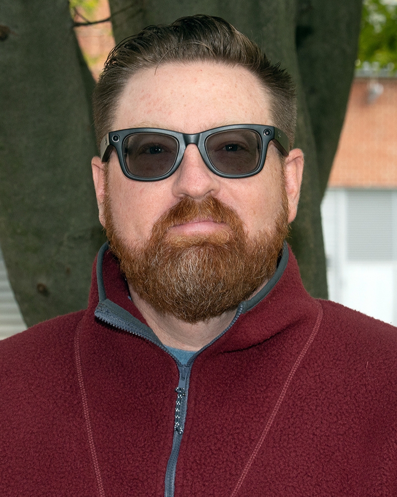a portrait of a man. he stands outside.