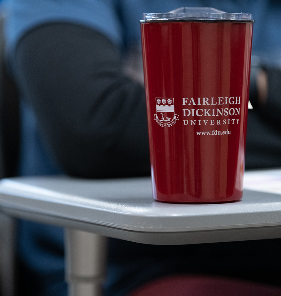 An FDU-branded water cup sits on a desk.