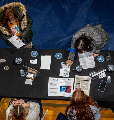 Students approach a table at a career fair. Image taken from above.