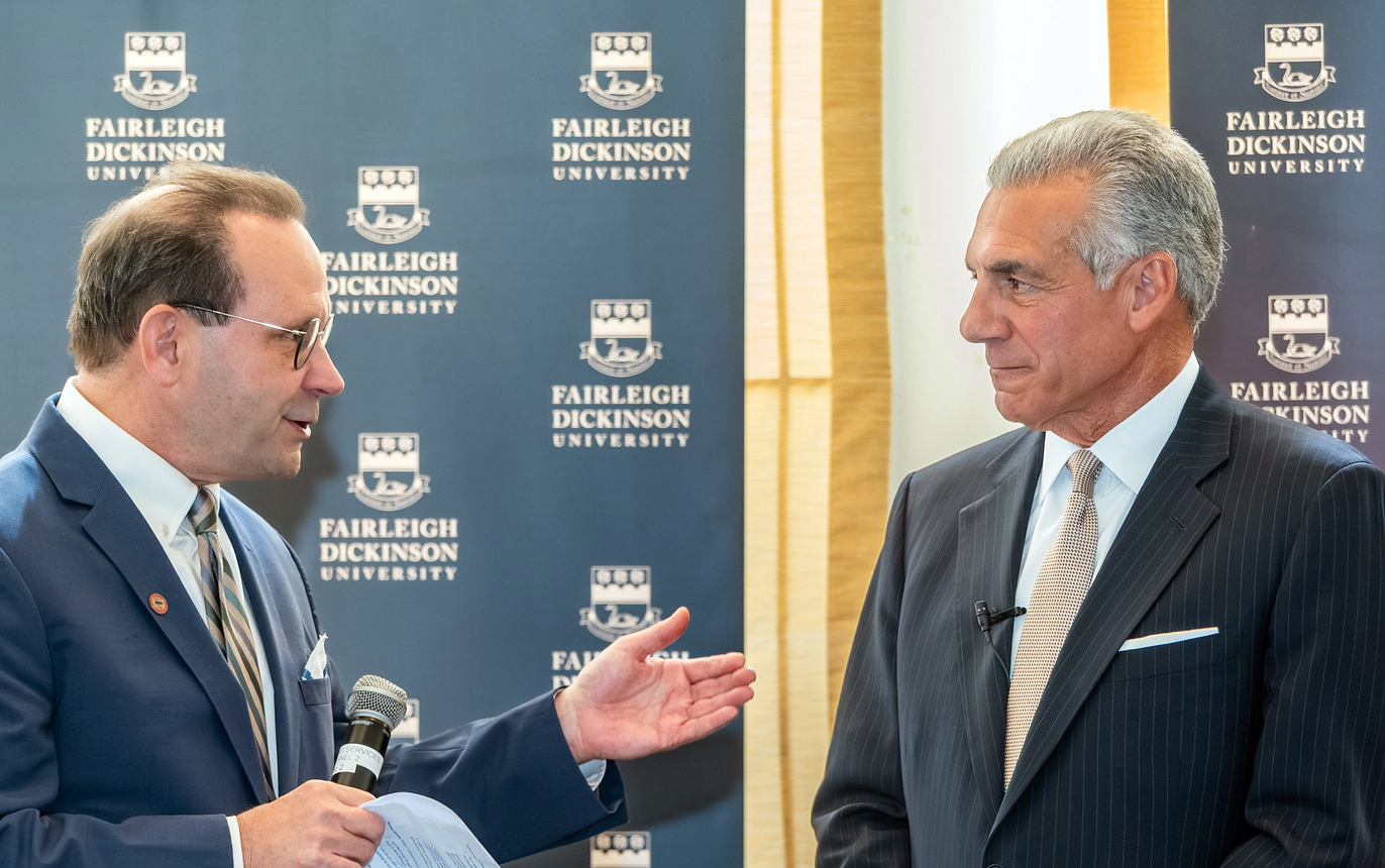 Two men in suits stand talking.