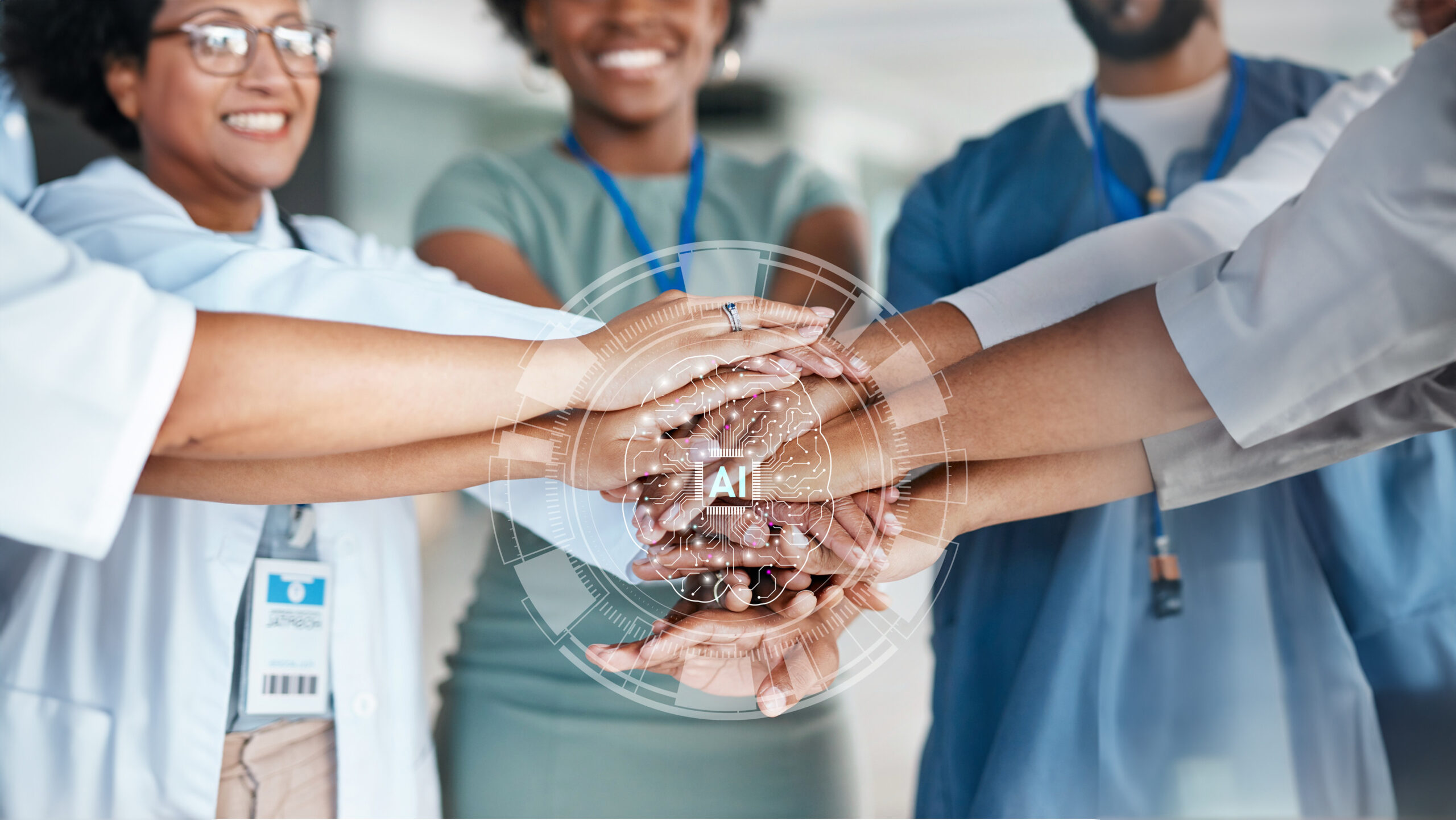 hands stacked together in a huddle. the people wear various scrubs and professional clothes. there is a graphic of a brain with the letters AI over the hands.