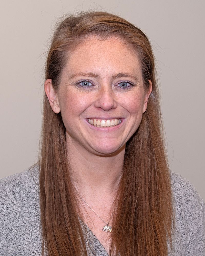 a headshot of a woman. she wears a gray sweater.