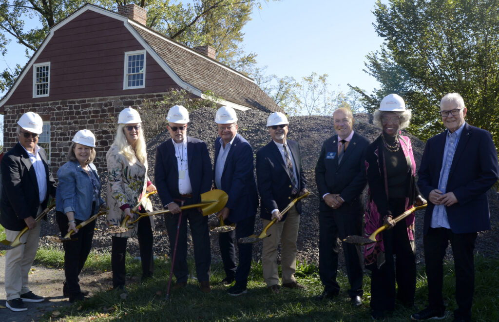 Group of people wearing hard hats and holding shovels to break ground on new construction