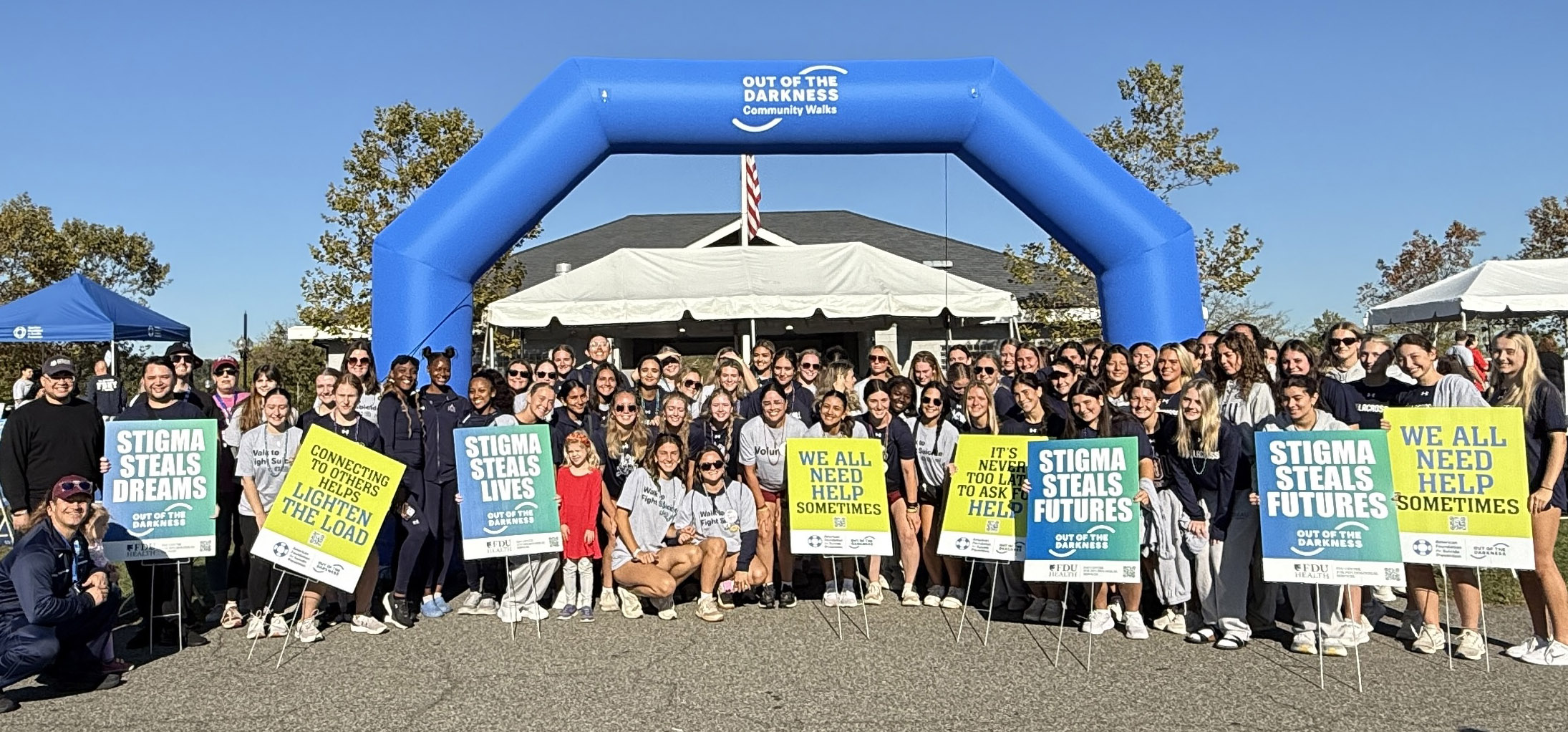 Group of faculty, staff and students holding banners at Overpeck Park