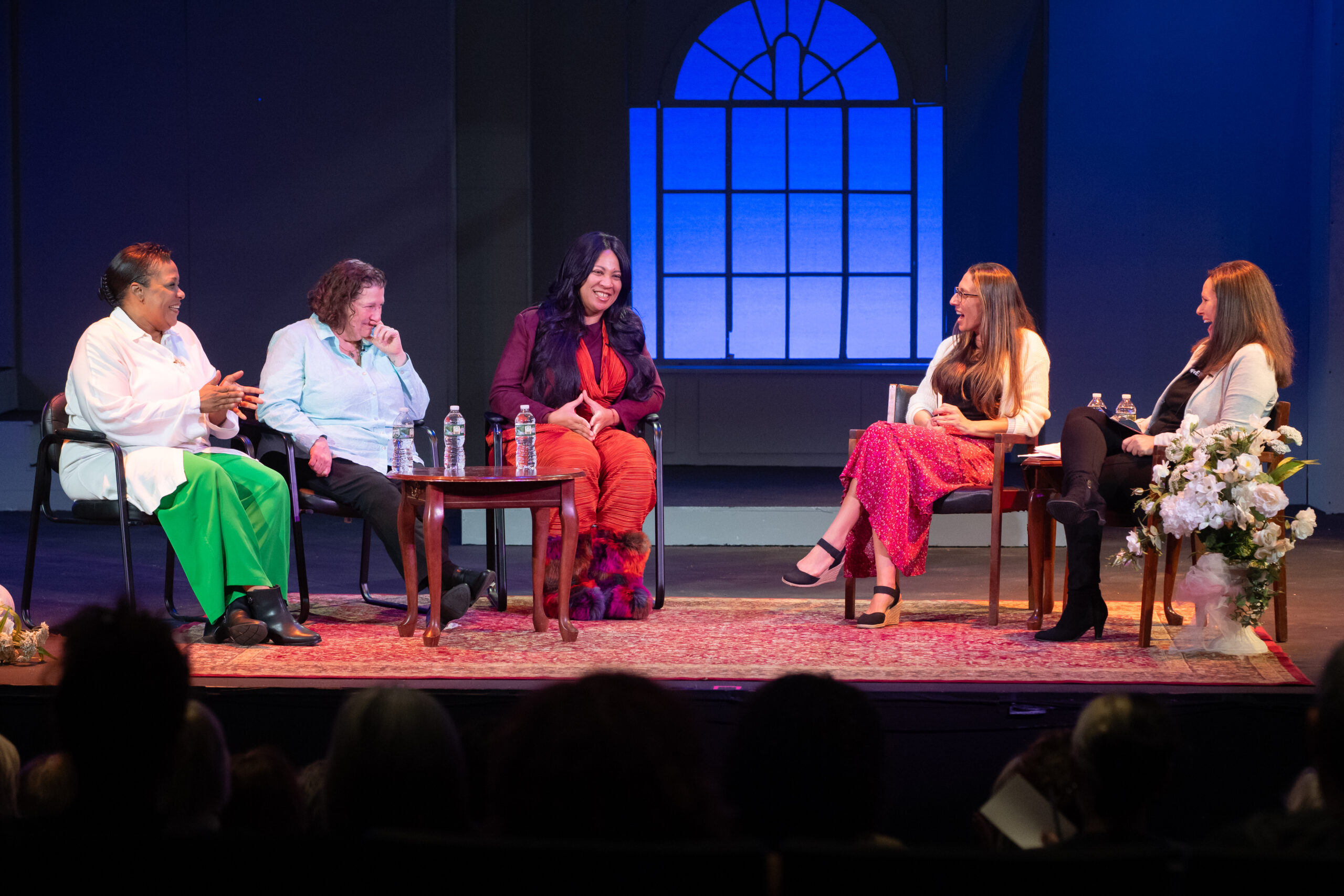 Five women sit on stage talking.