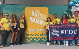 students and professors pose with an FDU flag and a HSI Battle of the Brains sign.