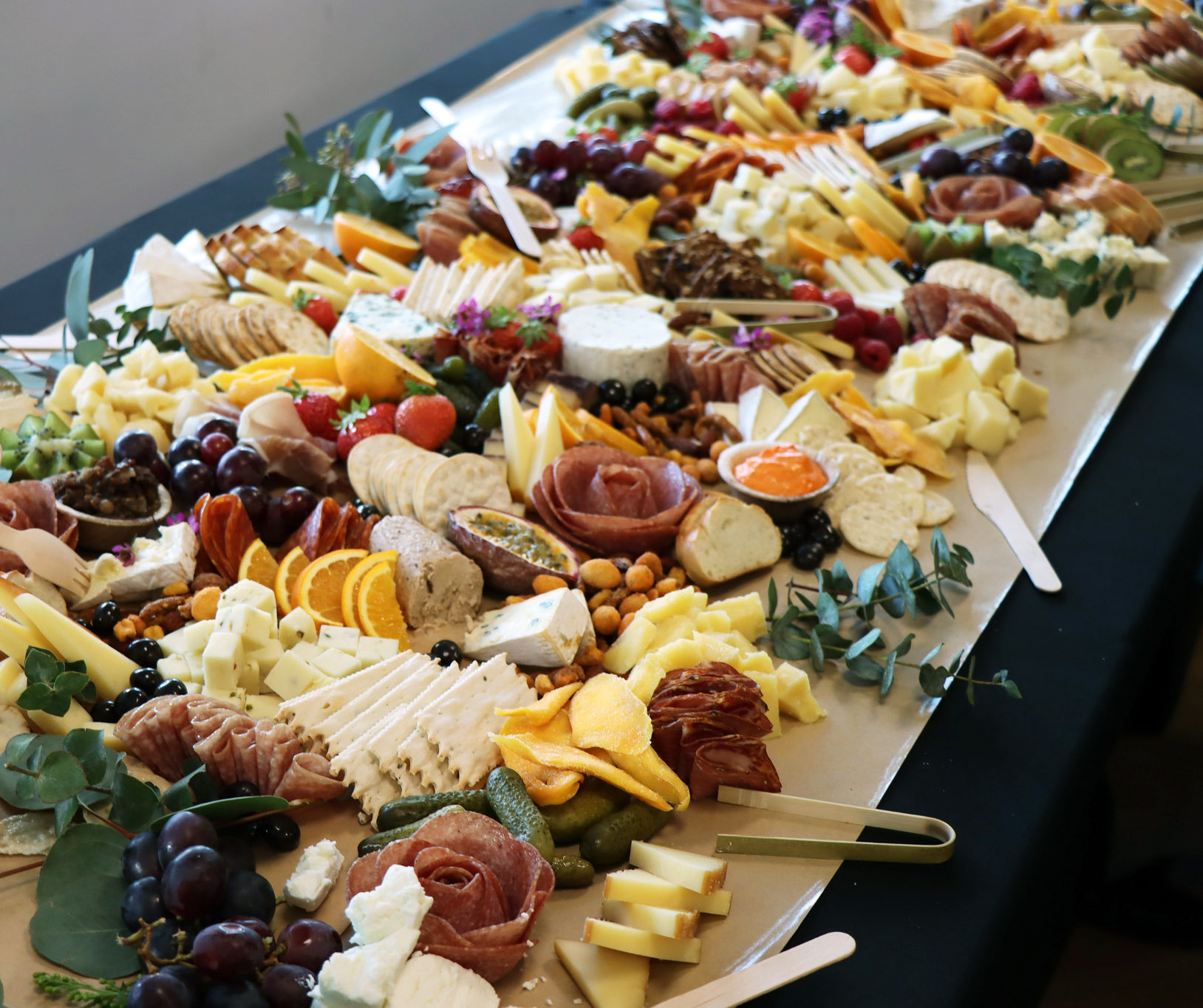 A cheese, meat, cracker and fruit spread on a long table.