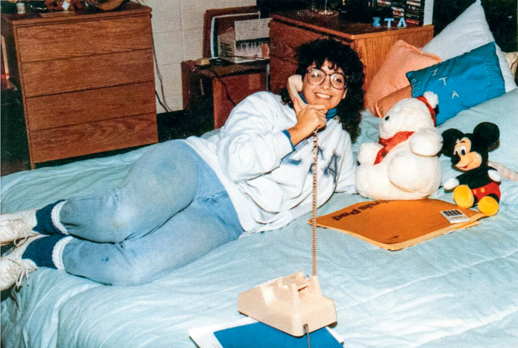 A vintage yearbook photo shows a student in a dorm making a call on a land line.
