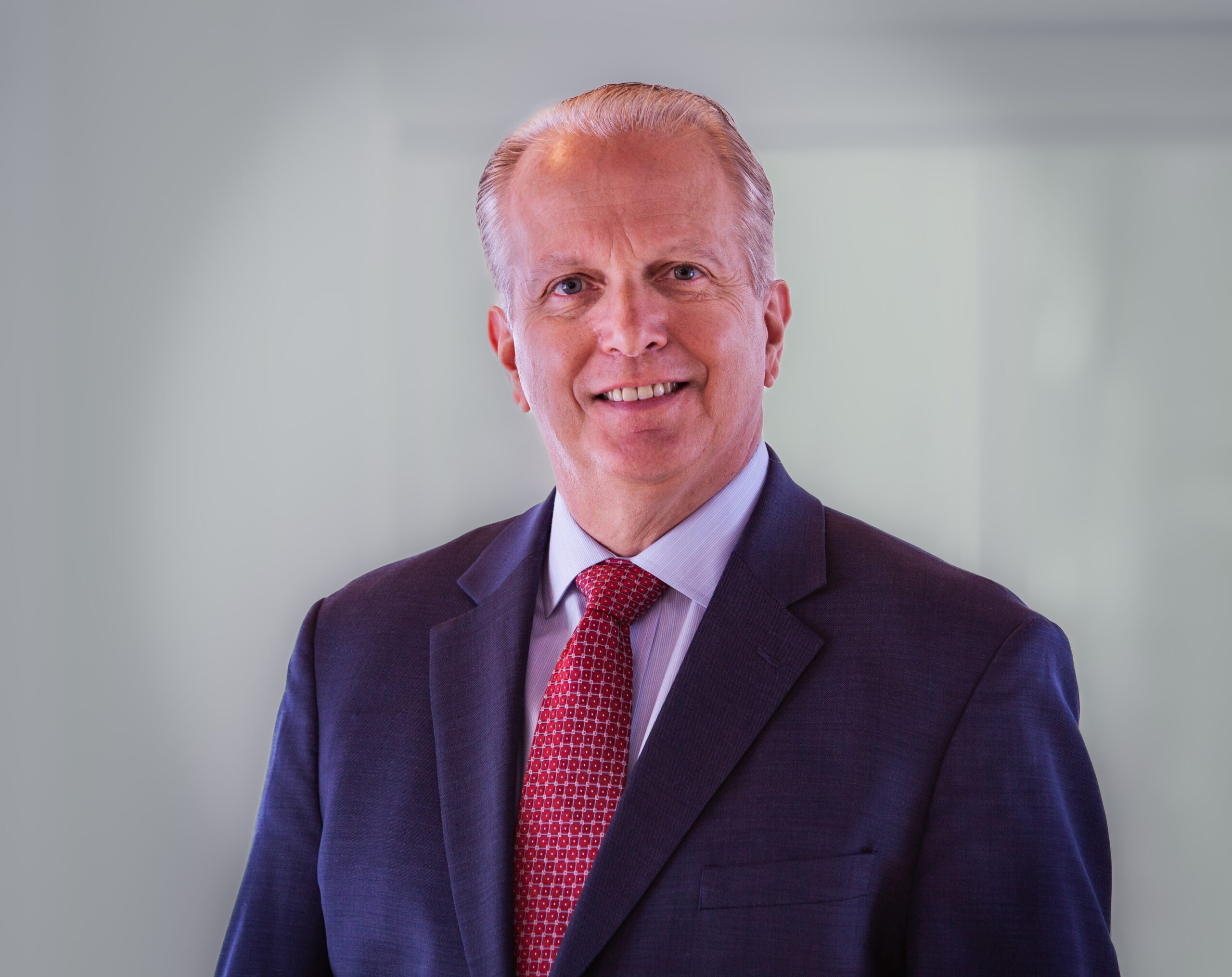 a headshot of a man. he wears a suit.
