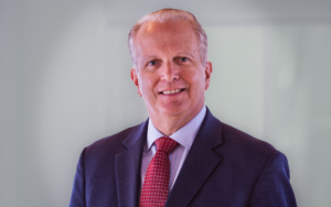 a headshot of a man. he wears a suit.