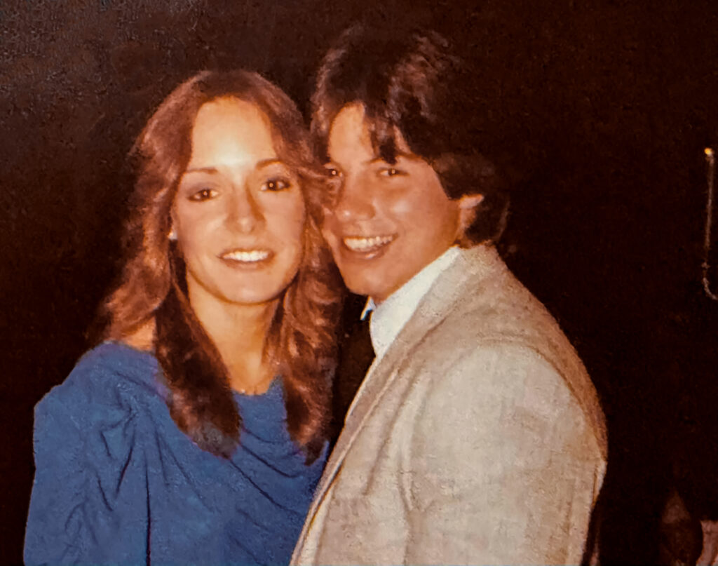 A couple in 1980s fashion smiles for the camera.