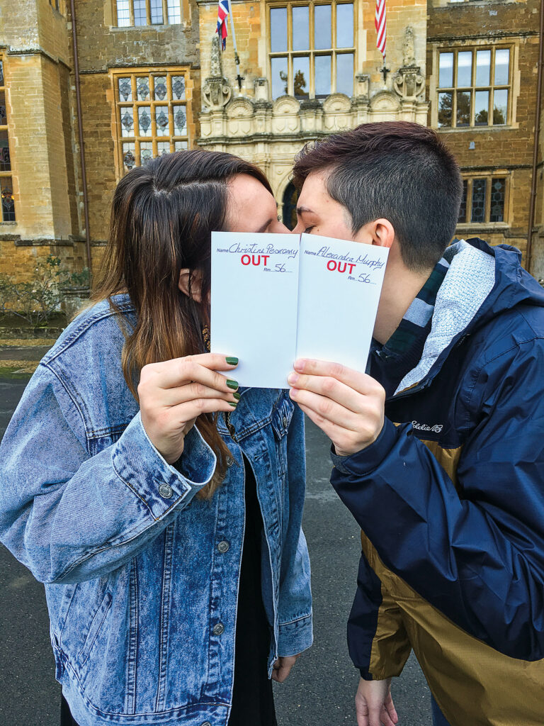 Two women kiss behind their fire cards.