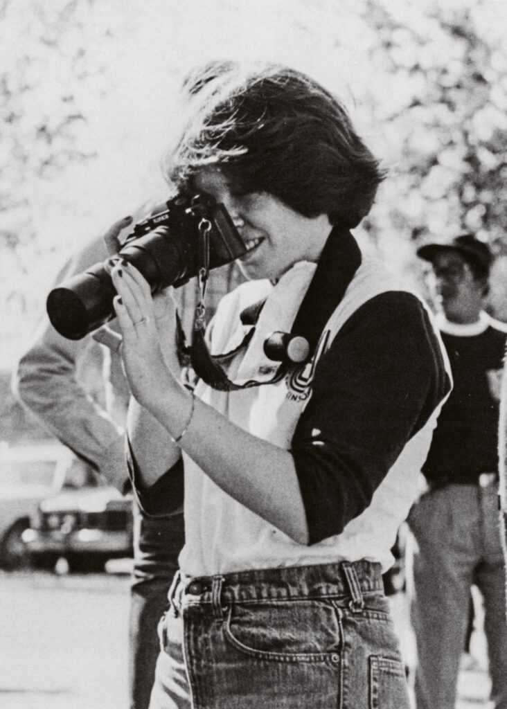 A student adjusts the focus on a long lens camera.