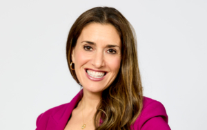 a headshot of a woman. she wears a pink blazer and matching pants.