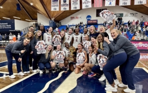 the FDU Knights Women's basketball team. they hold signs that read "ticket punched" and a championship trophy.