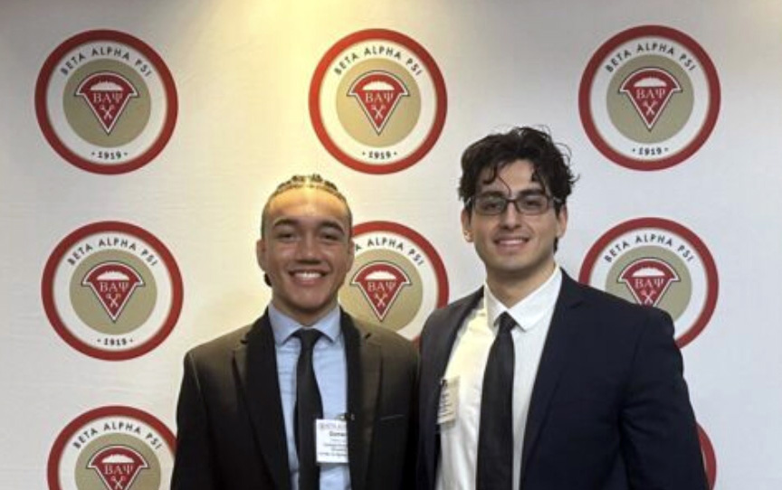 two men stand in front of a backdrop.