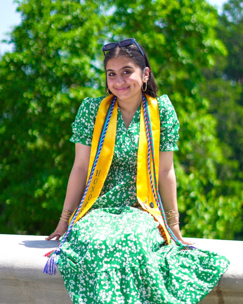A young woman sits outside on a wall.