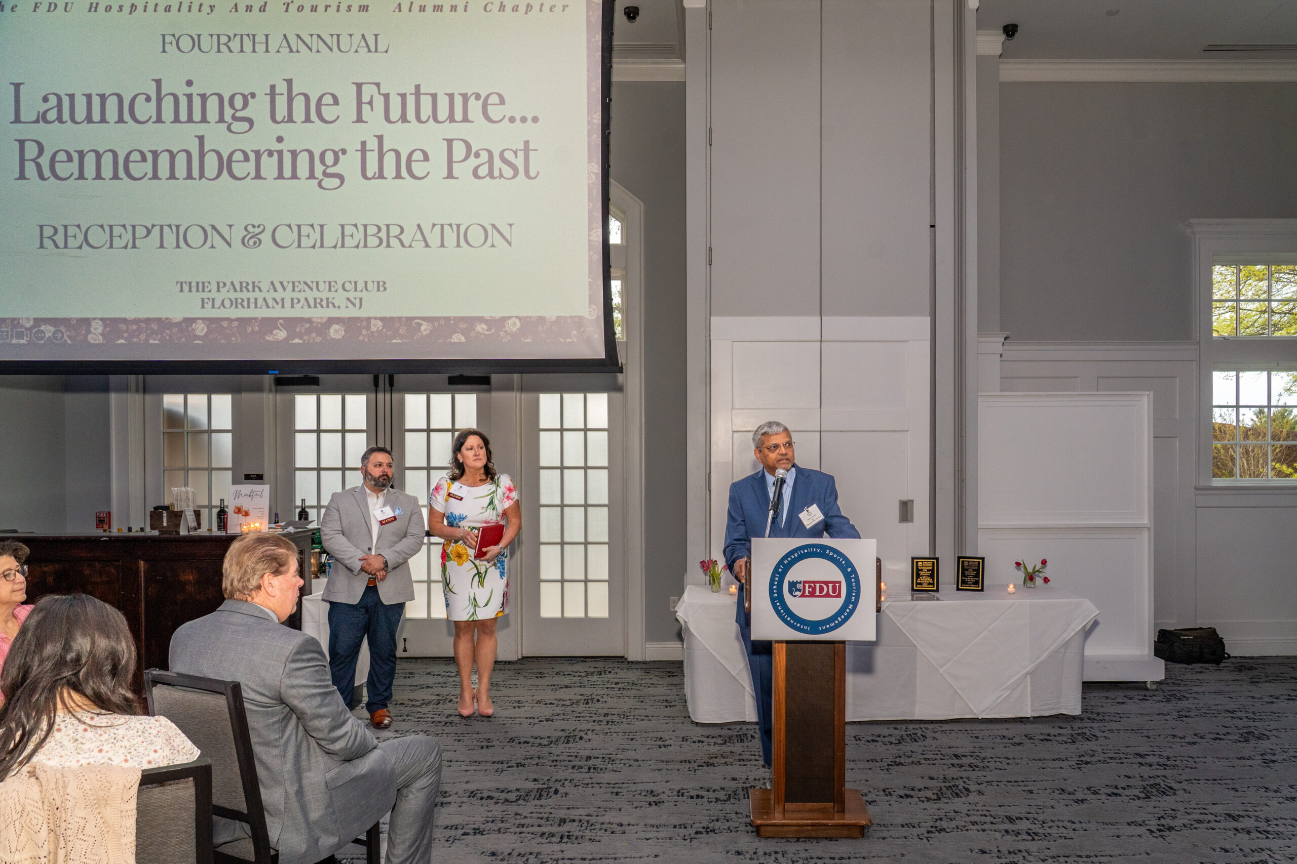 A man stands at a podium addressing an audience. 