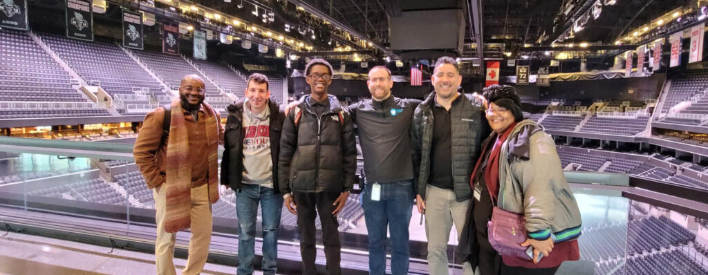 Six smiling students in the Barclays sports arena