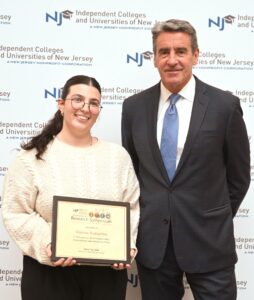 A female college student stands next to a man in a suit.
