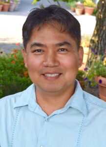 Smiling photo of a man wearing a light blue polo shirt
