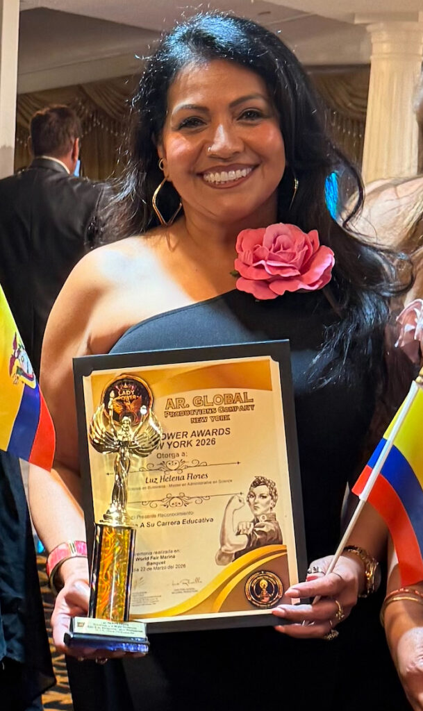 A smiling woman wearing a black gown holds up a plaque.