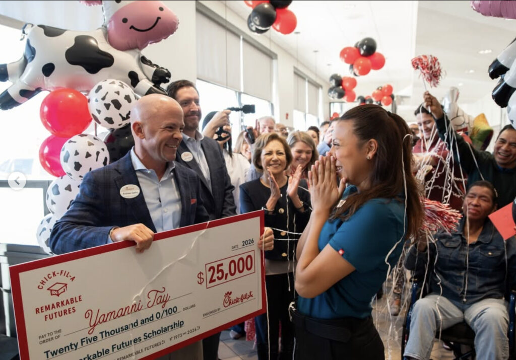A man holds a large check for $25,000 and presents it to a young woman.
