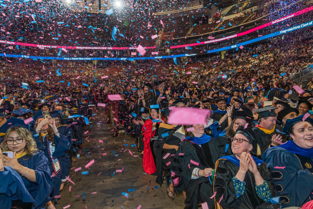 A crowd of graduates is covered in confetti.
