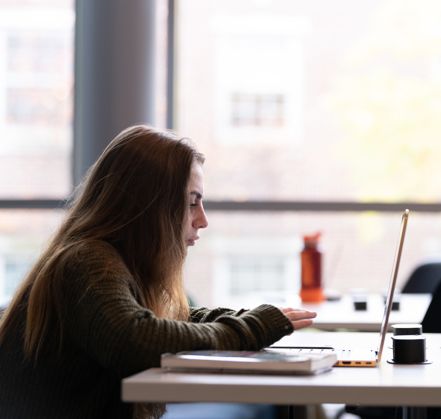 A female student studies on her laptop at the library.