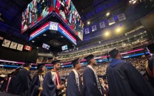 Students in caps and gowns line up at graduation.